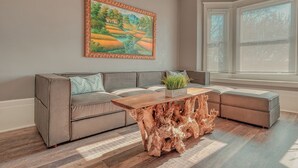 A living room with a sectional sofa, a wooden coffee table, and a painting on the wall. - BurgBnB Riverfront (Harrisburg)