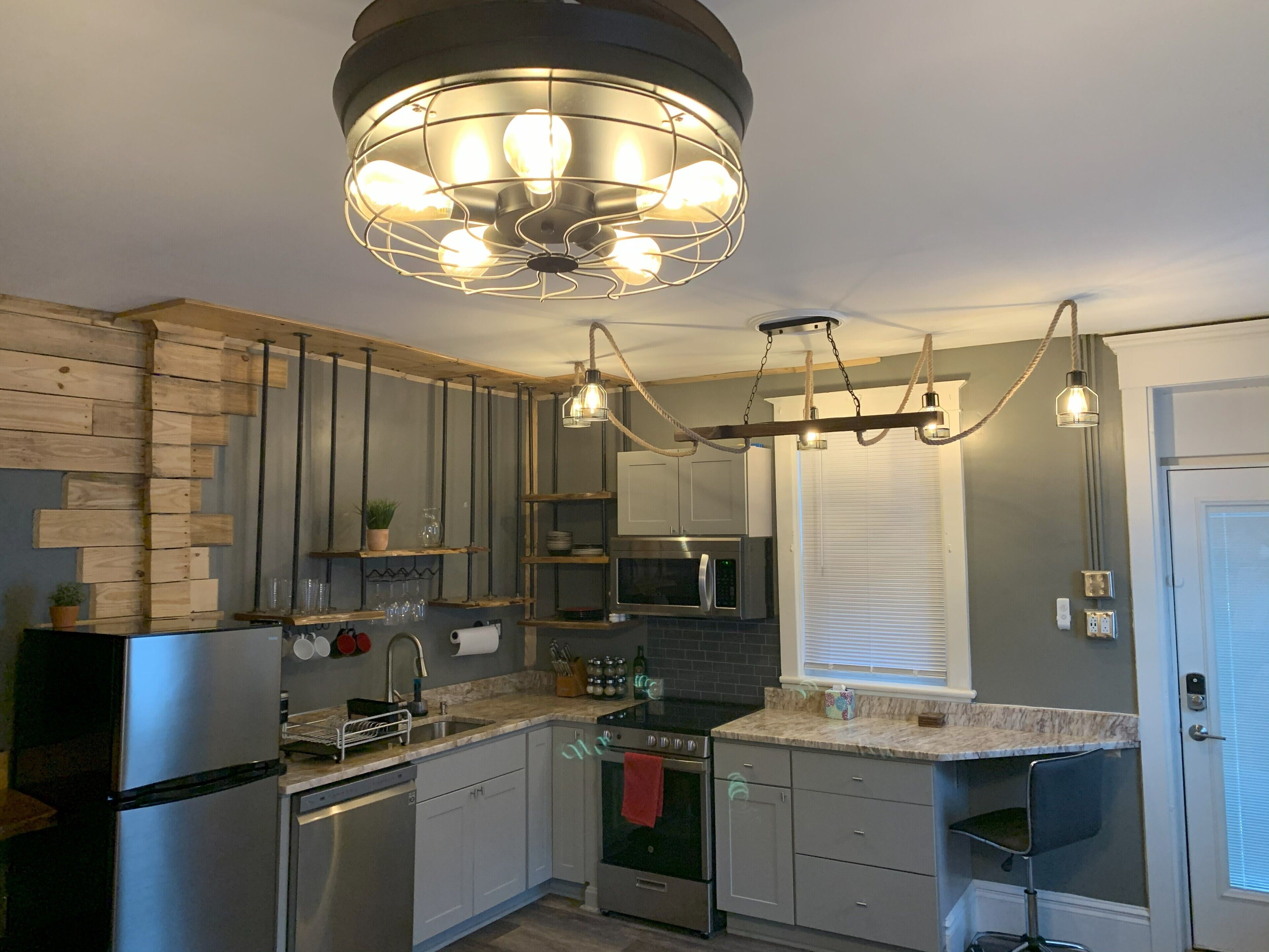 A modern kitchen with stainless steel appliances, wooden accents, and a unique pendant light fixture.