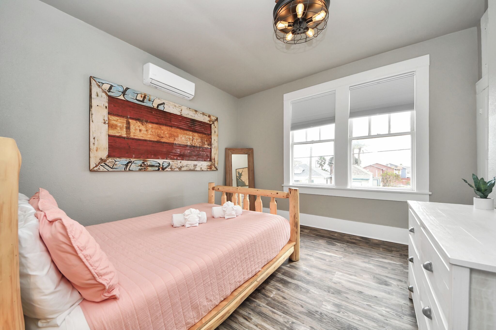 A bedroom with a bed, a window, a dresser, and a wall-mounted air conditioner.