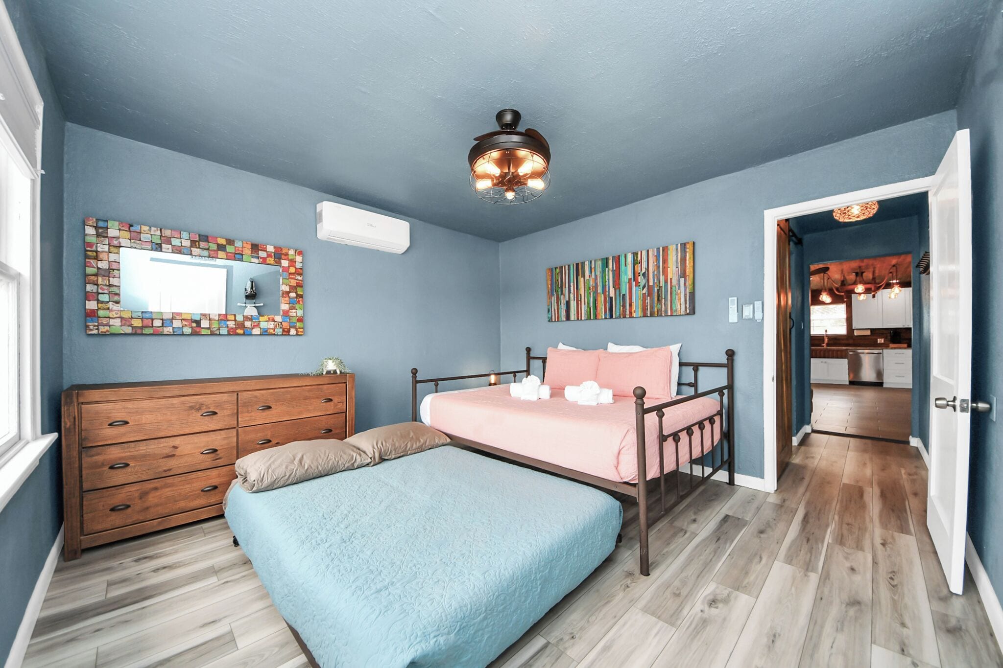 A bedroom with a bed, dresser, and a ceiling fan.