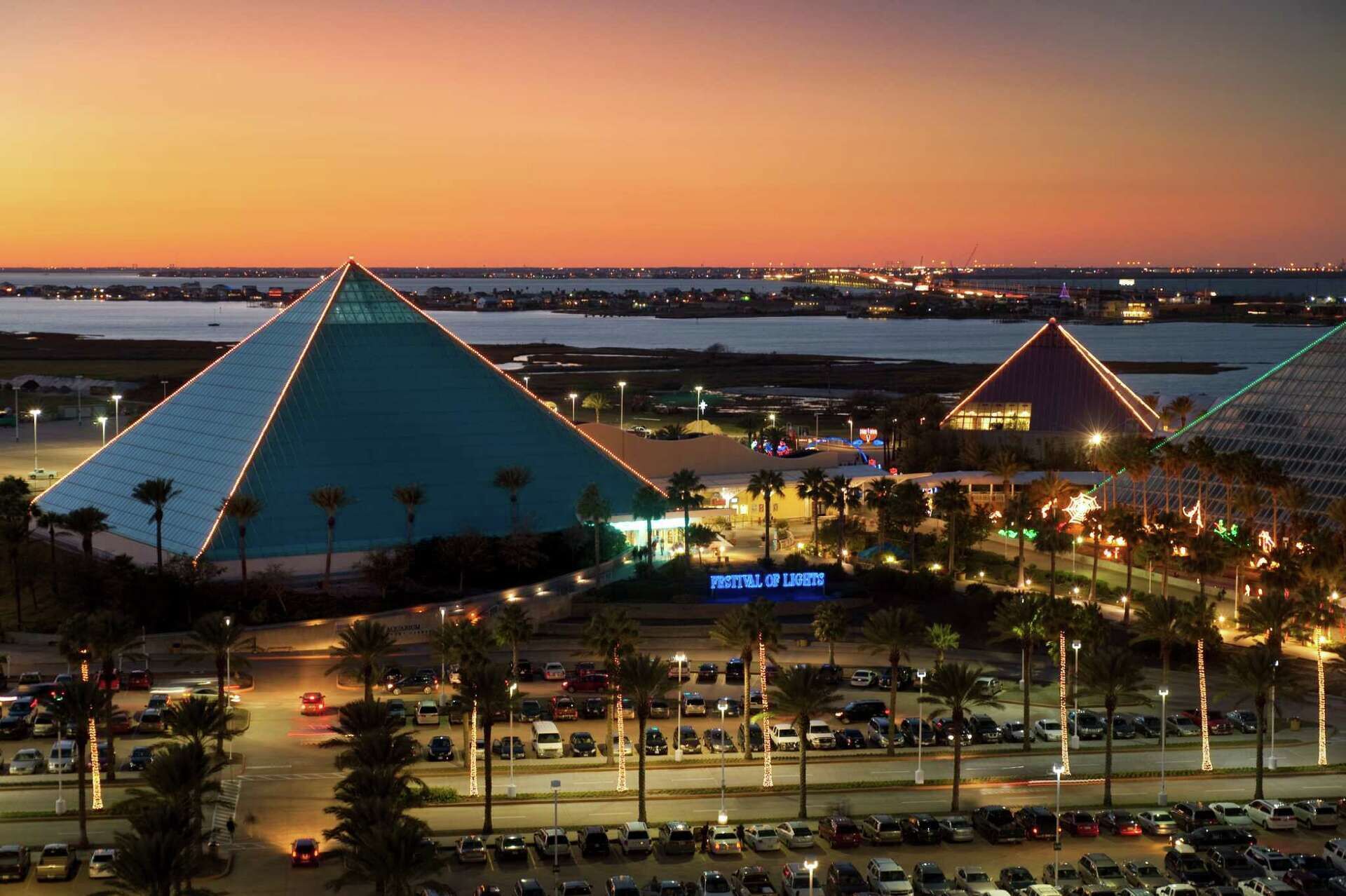 A parking lot with multiple cars, a large pyramid-shaped building, and a sign that reads "Festival of Lights".