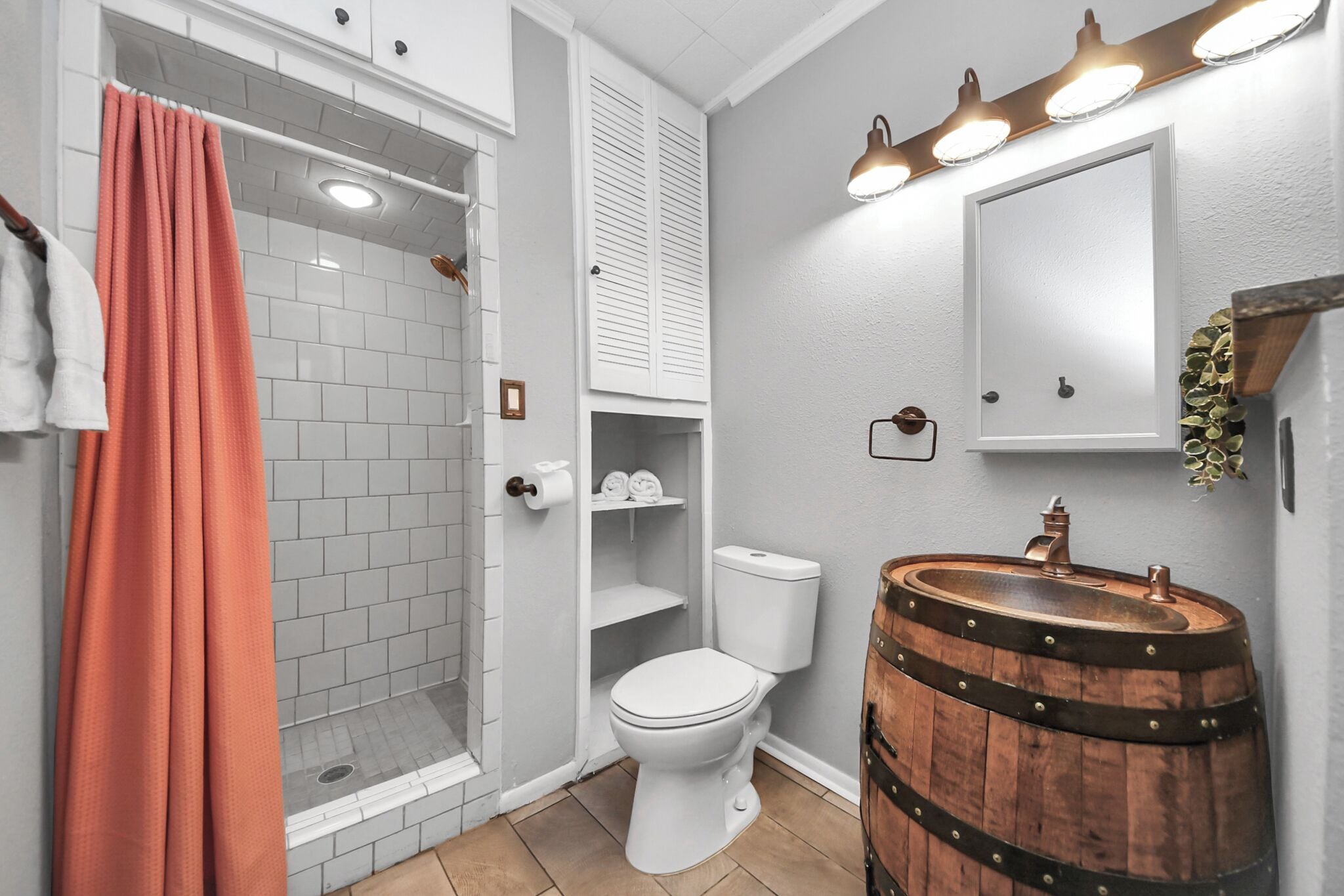A bathroom with a shower, toilet, and a sink with a wooden barrel base.