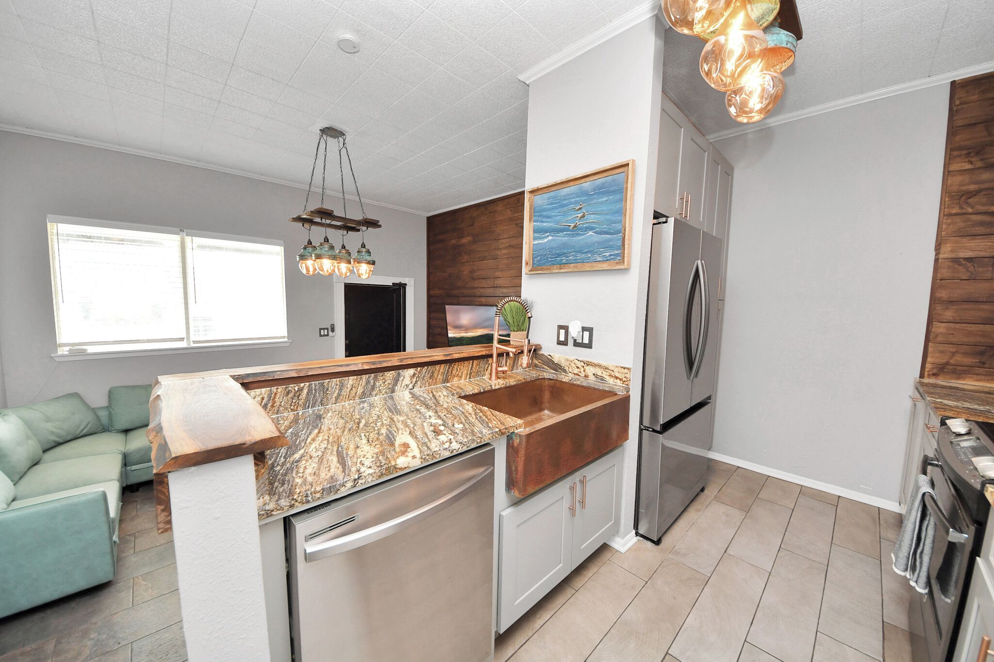 A modern kitchen with a central island, stainless steel appliances, and a wooden backsplash.