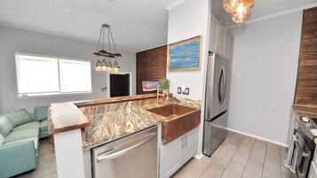 A modern kitchen with a central island, stainless steel appliances, and a wooden backsplash.