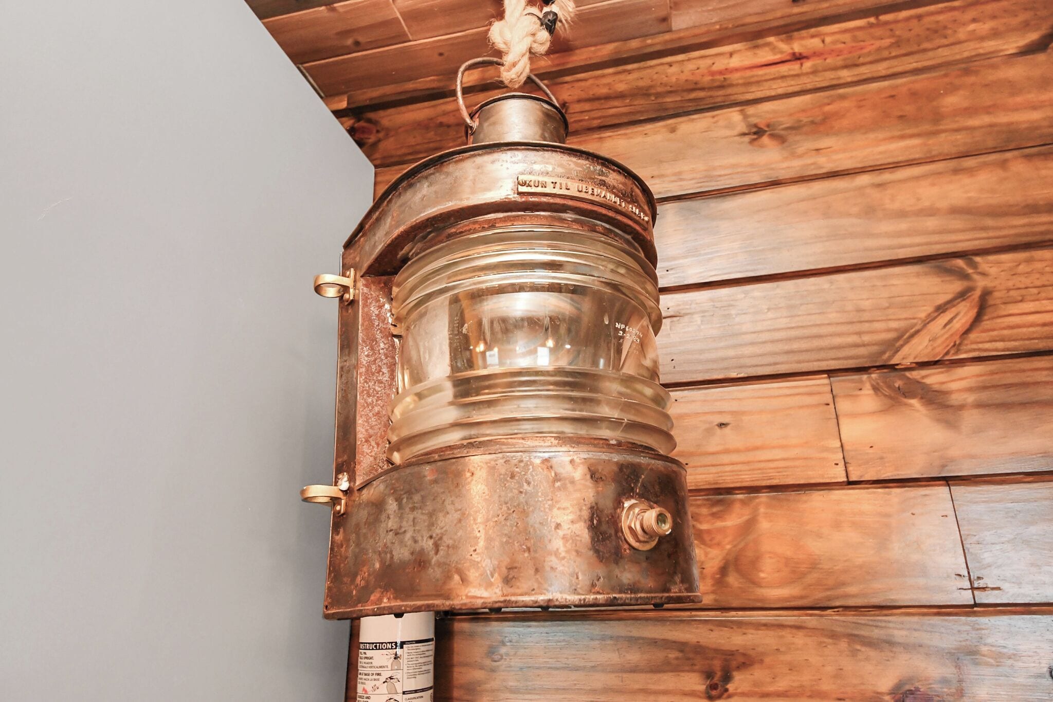 Ein Metallbehälter mit Seilhenkel, an einer Holzwand befestigt.