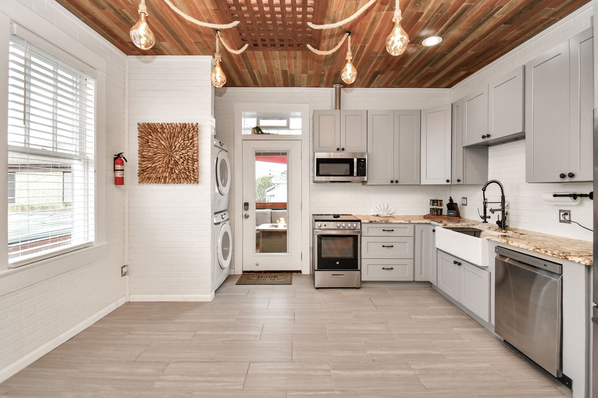 Una cocina moderna con armarios blancos, electrodomésticos de acero inoxidable y techo de madera.
