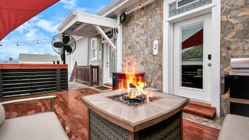 A deck with a fire pit, outdoor furniture, and a stone wall.