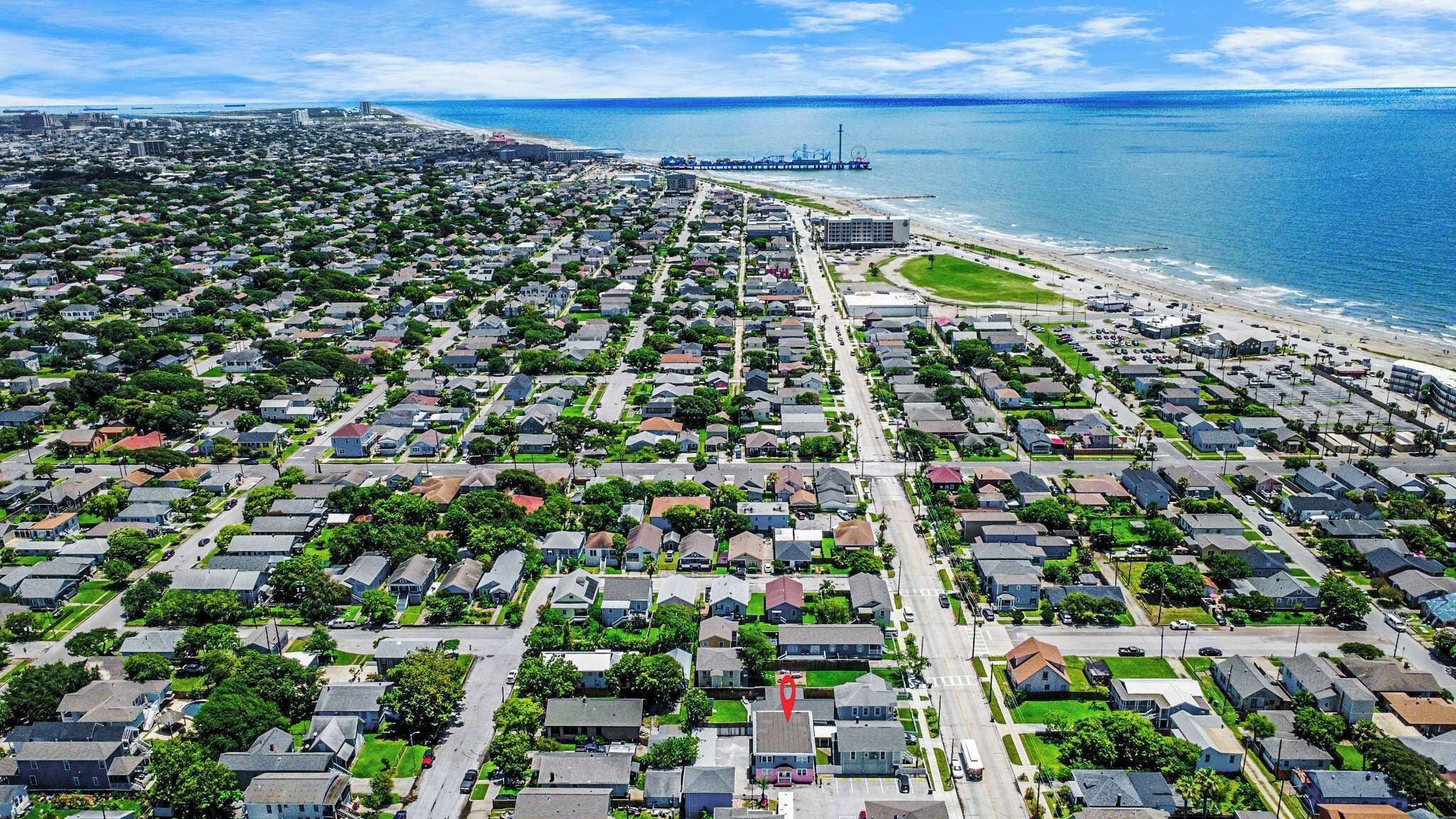 An aerial view of a coastal residential area with houses, roads, and a beach.