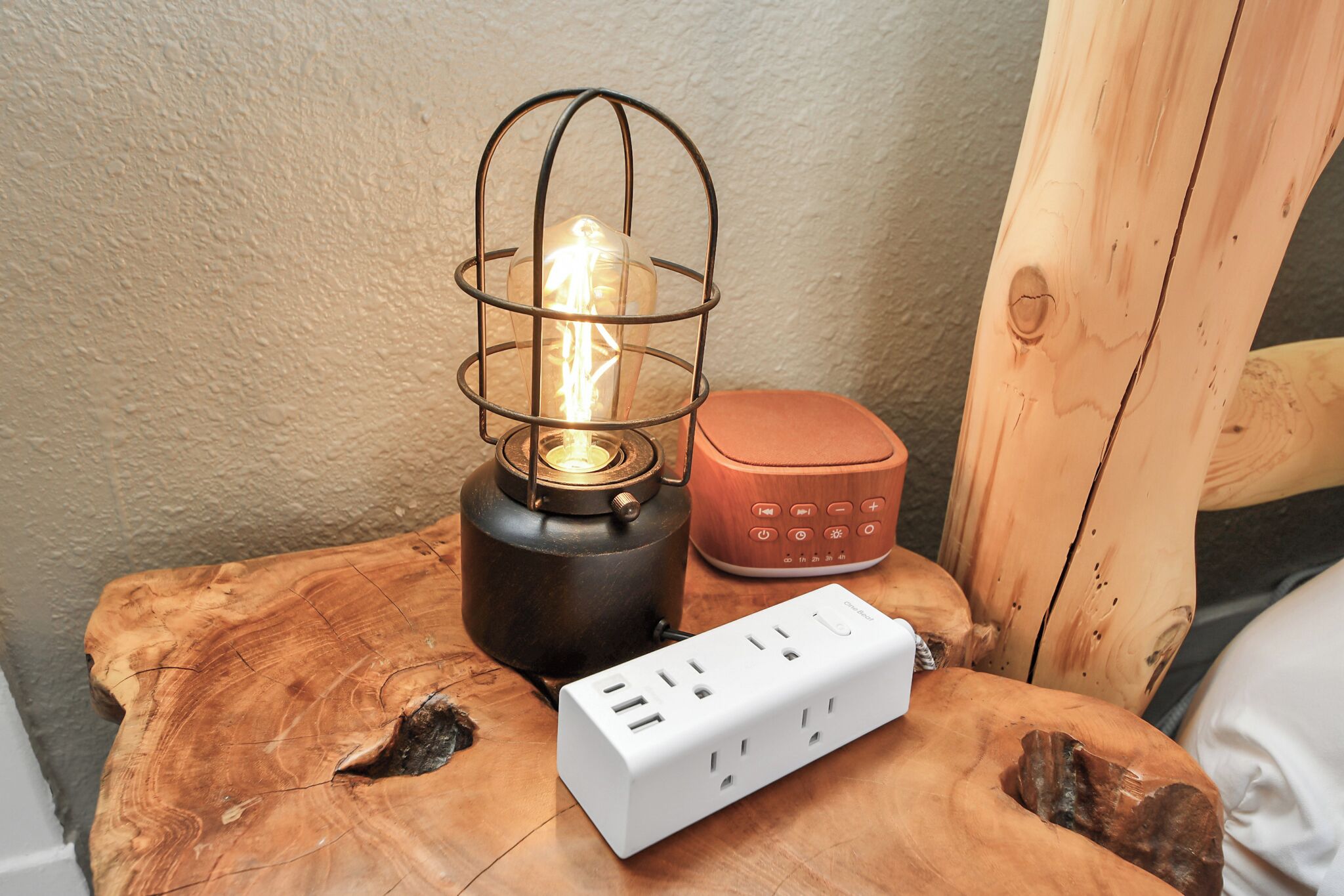 A wooden table with a power strip, a metal lantern, and a wooden speaker.