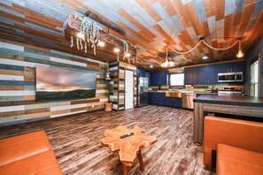 A modern kitchen with dark blue cabinets, stainless steel appliances, and a wooden island. - Gulf Siesta Vacation Lofts (Galveston)