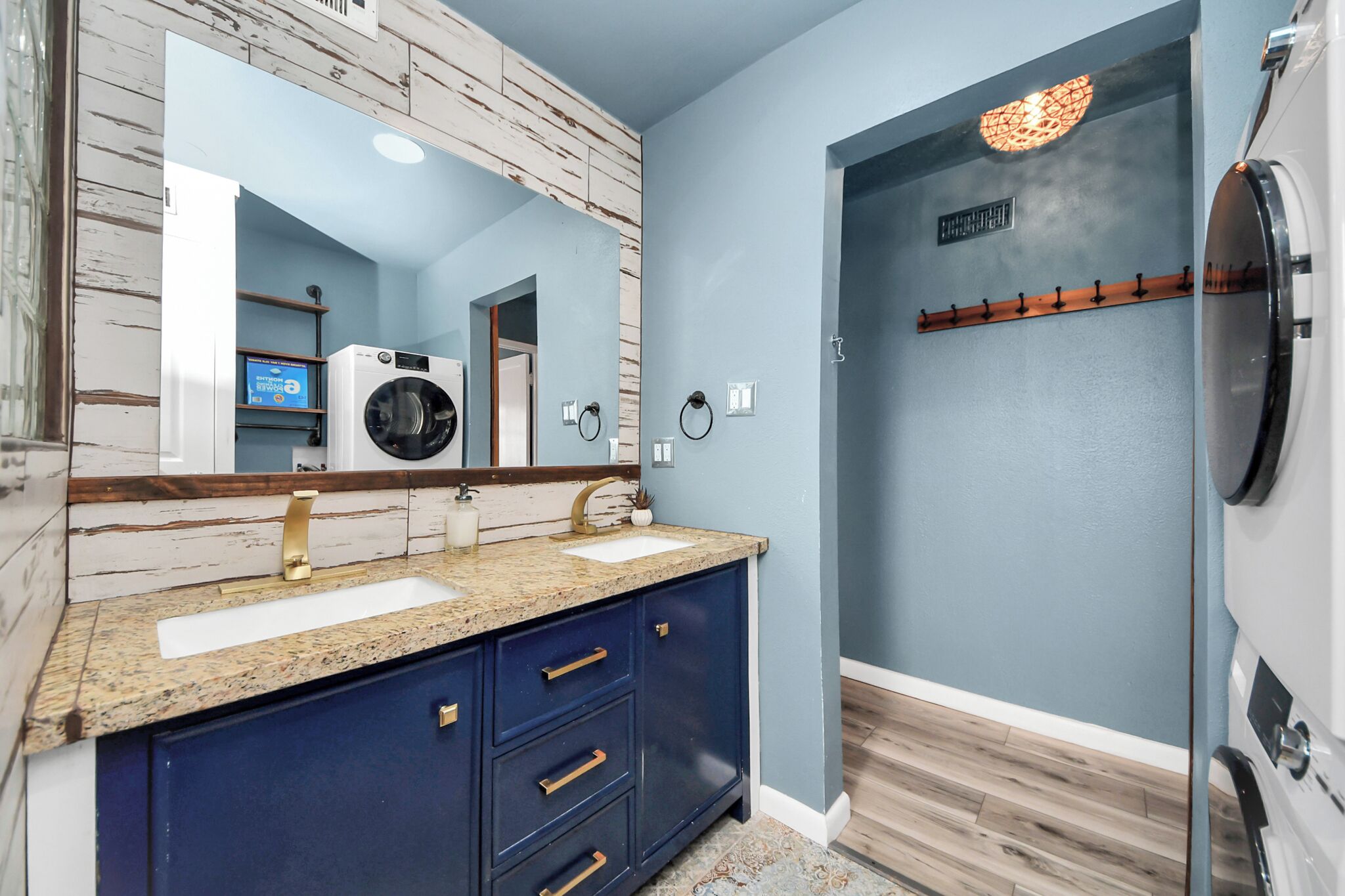 A bathroom with a double sink vanity, a large mirror, a wall-mounted heater, and a shower area.