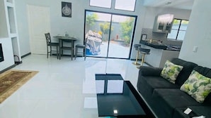 Ein modernes Wohnzimmer mit einer schwarzen Couch, einem Couchtisch und einem Essbereich mit Tisch und Stühlen.