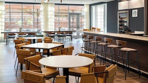 Un restaurant moderne avec des tables rondes et des tabourets de bar, de grandes fenêtres et une enseigne Starbucks.