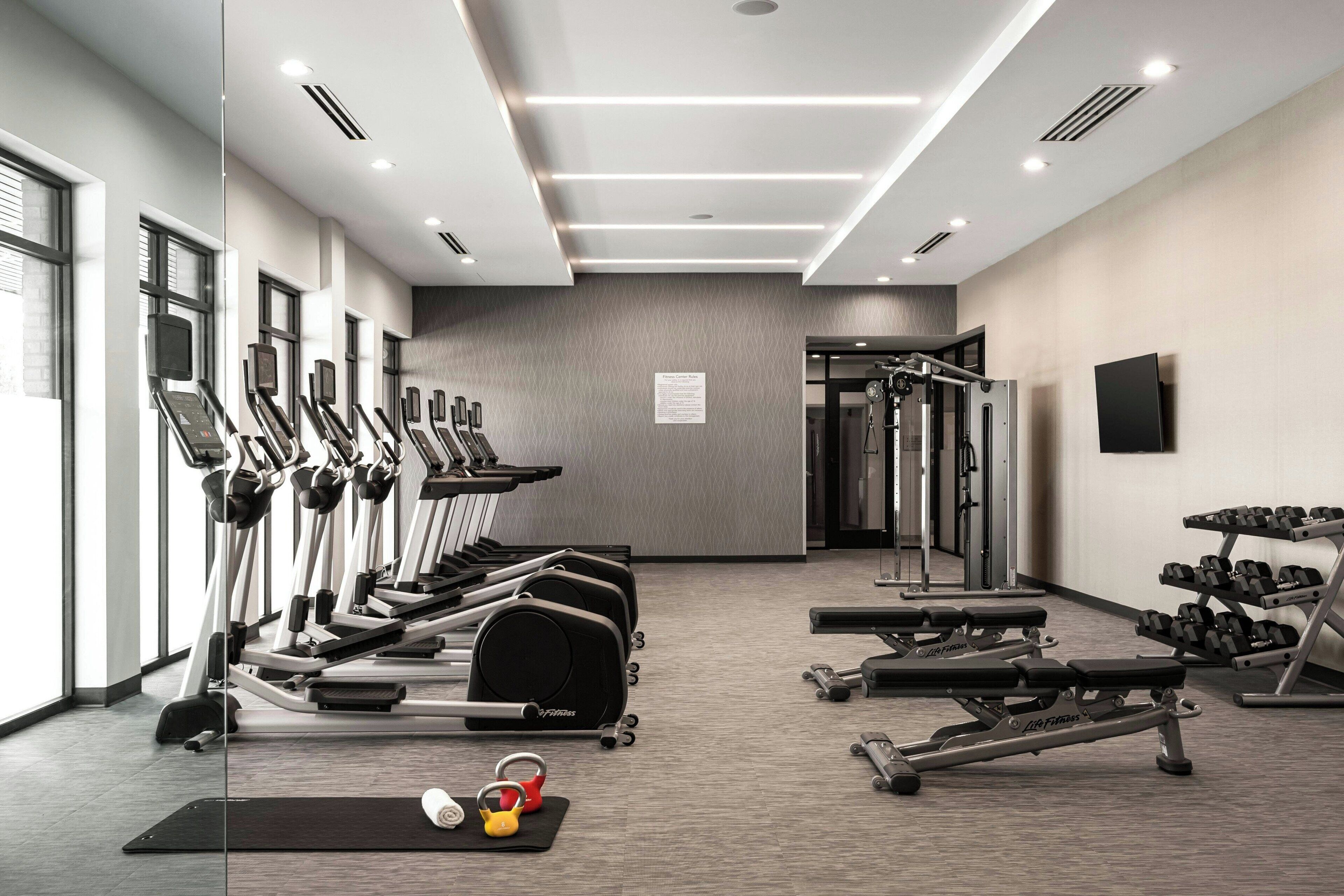 Une salle de sport moderne équipée de tapis de course, d’appareils de musculation et d’haltères.