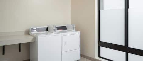 A laundry area with a washing machine and dryer, a countertop, and a large window.