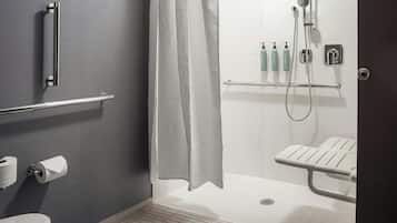Et moderne badeværelse med bruser, gelænder, toilet og håndtørrer.