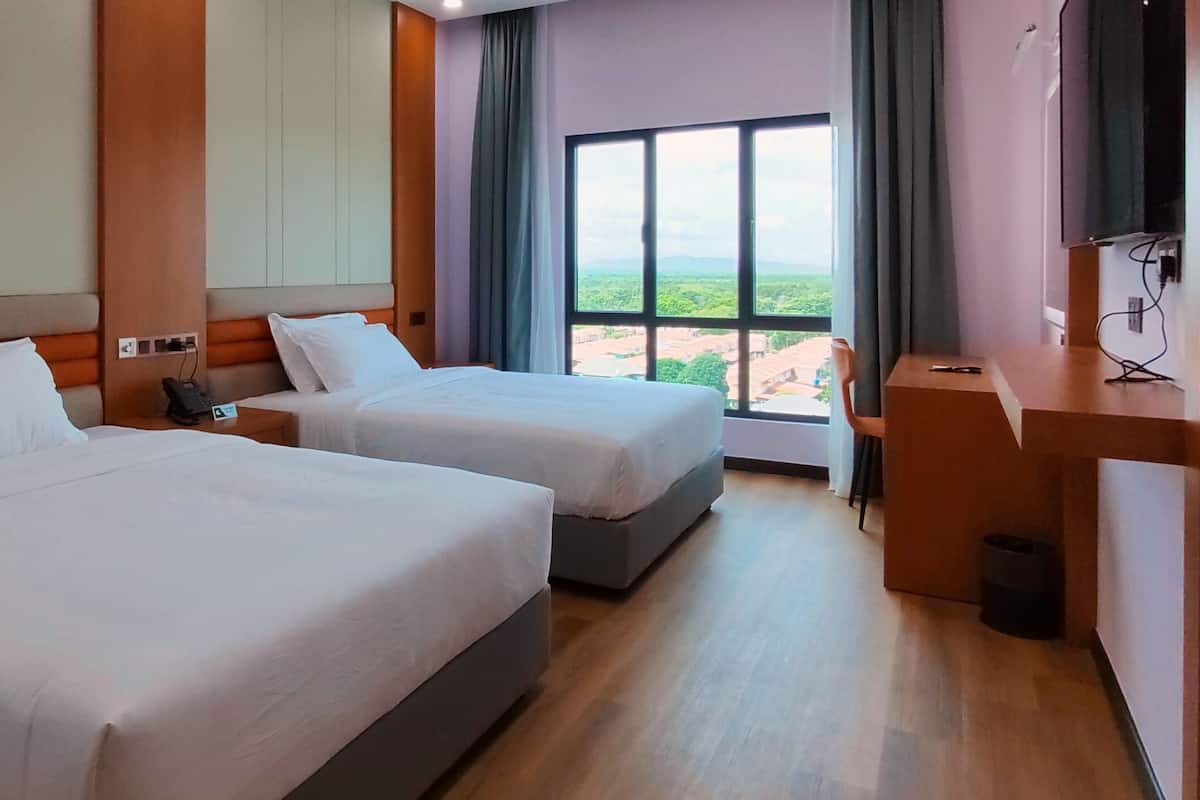 A hotel room with two beds, a desk, and a large window offering a city view.