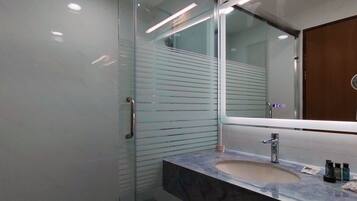 A modern bathroom with a glass shower enclosure, a marble sink, and a large mirror.
