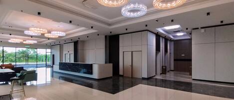 A modern hotel lobby with a reception desk, large windows, and decorative lighting.