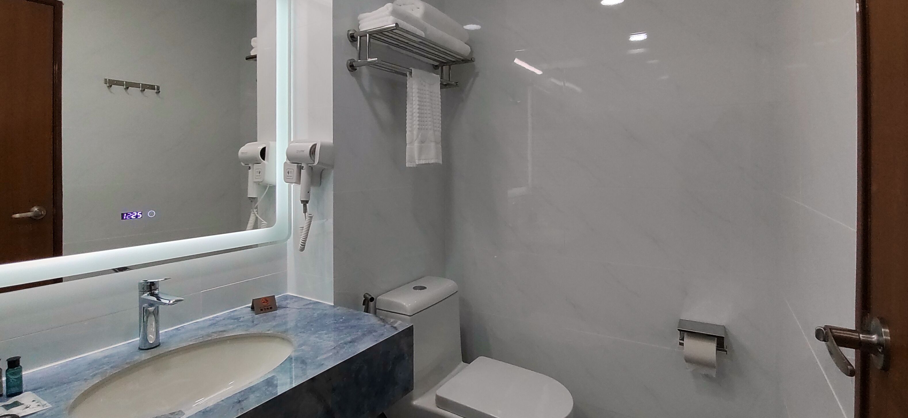 A bathroom with a marble sink, a toilet, a towel rack, and a hand dryer.