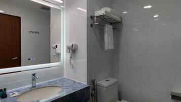 A modern bathroom with a marble sink, a mirror, a towel rack, a hand dryer, and a toilet.
