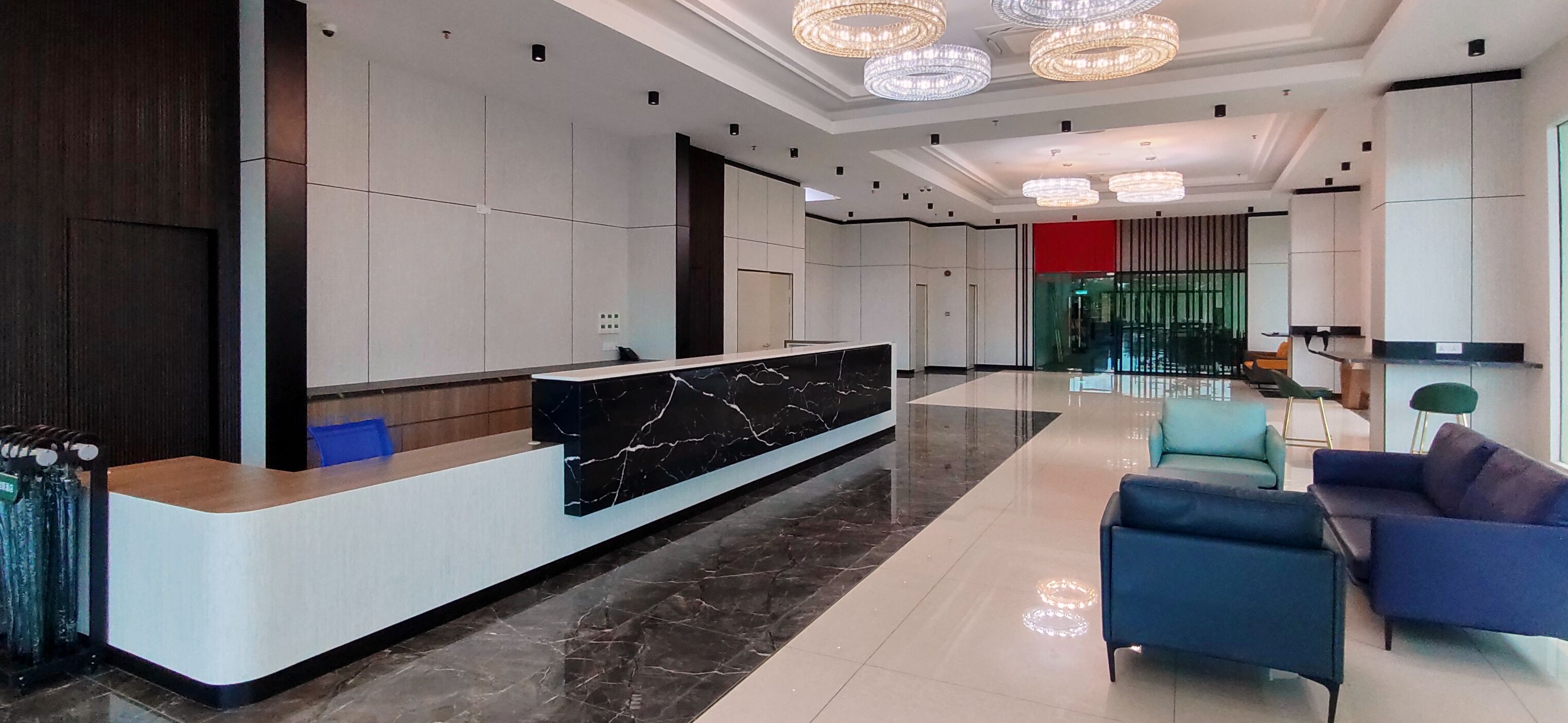 A modern hotel lobby with a marble reception desk, plush seating, and contemporary lighting fixtures.
