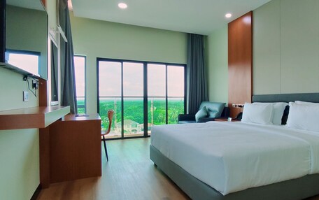 Habitación de hotel moderna con una cama grande, un escritorio y una silla. Hay un ventanal con vistas a la ciudad.