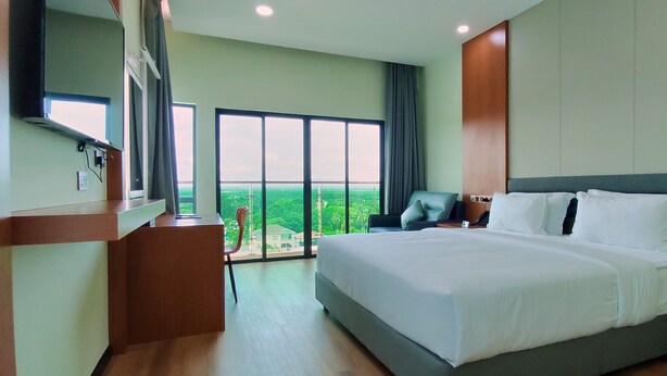 A modern hotel room with a large bed, a desk, and a chair. There is a large window with a view of the city. - Hotel Kapalai (Semporna)