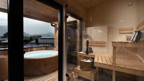 Een houten sauna met een whirlpool, houten banken en een stenen vloer.