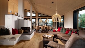 Een moderne woonkamer met een open haard, een bank en een eethoek.