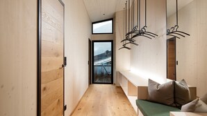 Een moderne hal met houten vloeren, een bankje en een stadszicht door een groot raam.