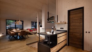 Een moderne keuken met een centraal eiland, houten vloeren en een eethoek met stoelen en een tafel.