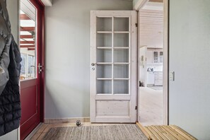 A door with a glass panel, a red door on the left, and a bench in the foreground.