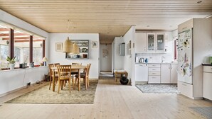 Eine geräumige Küche mit Holzboden, ein Essbereich mit Holztisch und -stühlen sowie ein Blick zu einem Flur.