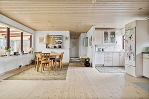 A spacious kitchen with wooden flooring, a dining area with a wooden table and chairs, and a view through to a hallway.