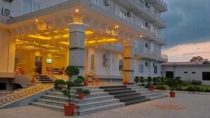 A hotel entrance with a covered outdoor area, steps leading up to the entrance, and potted plants. - Hotel Orion (Sunwal)