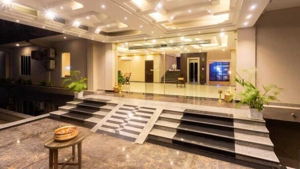 A modern hotel lobby with a marble floor, a reception desk, and a staircase leading to the upper floors. - Hotel Orion (Sunwal)