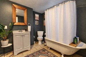 Een badkamer met een bad, toilet, wastafel en spiegel.