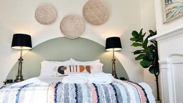 A neatly made bed with a striped blanket, two lamps, and three wall-mounted round decorations.