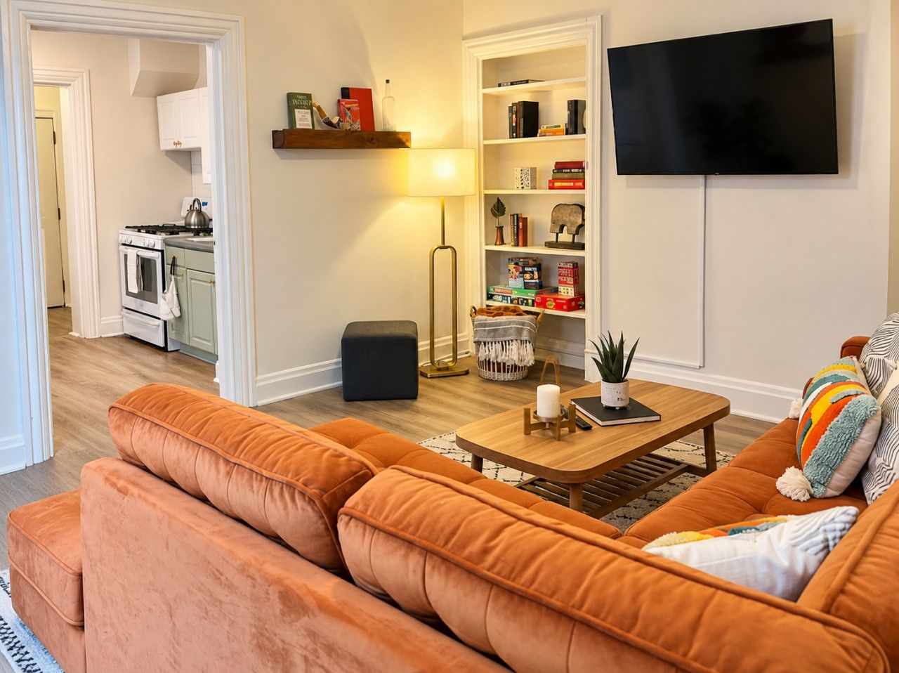 Ett vardagsrum med en soffa, ett soffbord, en lampa, en bokhylla och en tv-apparat med platt skärm.