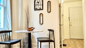 A dining area with a round table, two chairs, and a decorative vase.