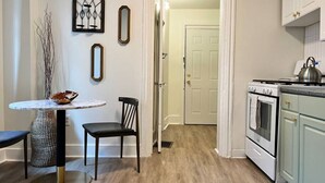 A kitchen with a stove, cabinets, and a dining area with a table and chairs.
