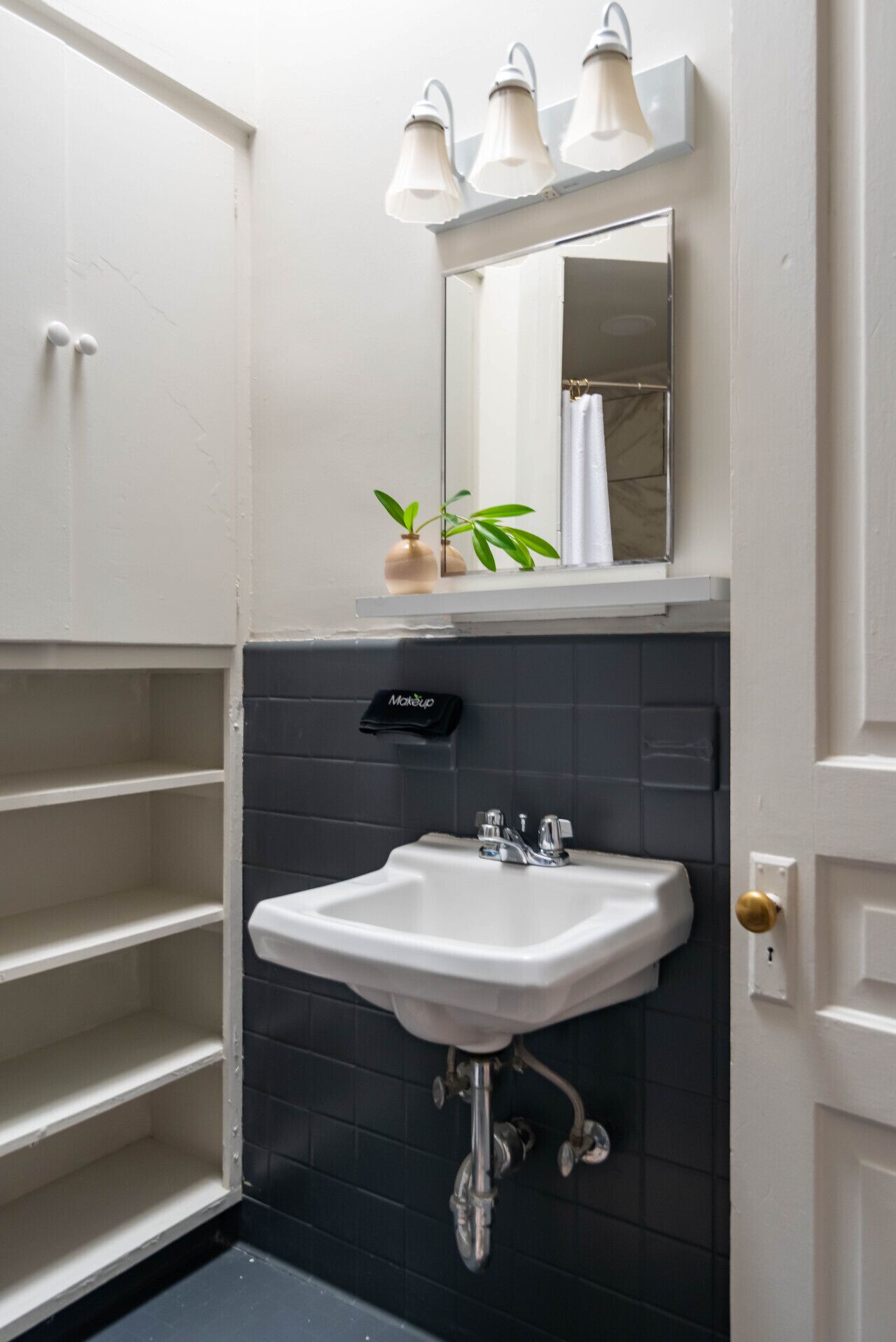 A bathroom with a white sink, a mirror, and three wall-mounted lights.