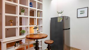 A compact kitchen with white cabinetry, a round wooden table, a built-in stove, and a refrigerator.