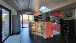 Una cocina moderna con una isla central, sillas de madera y un ventanal amplio.