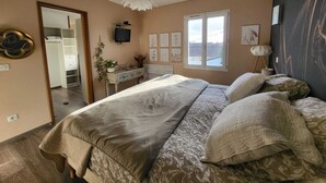 Un dormitorio con cama, escritorio, televisión y ventana.