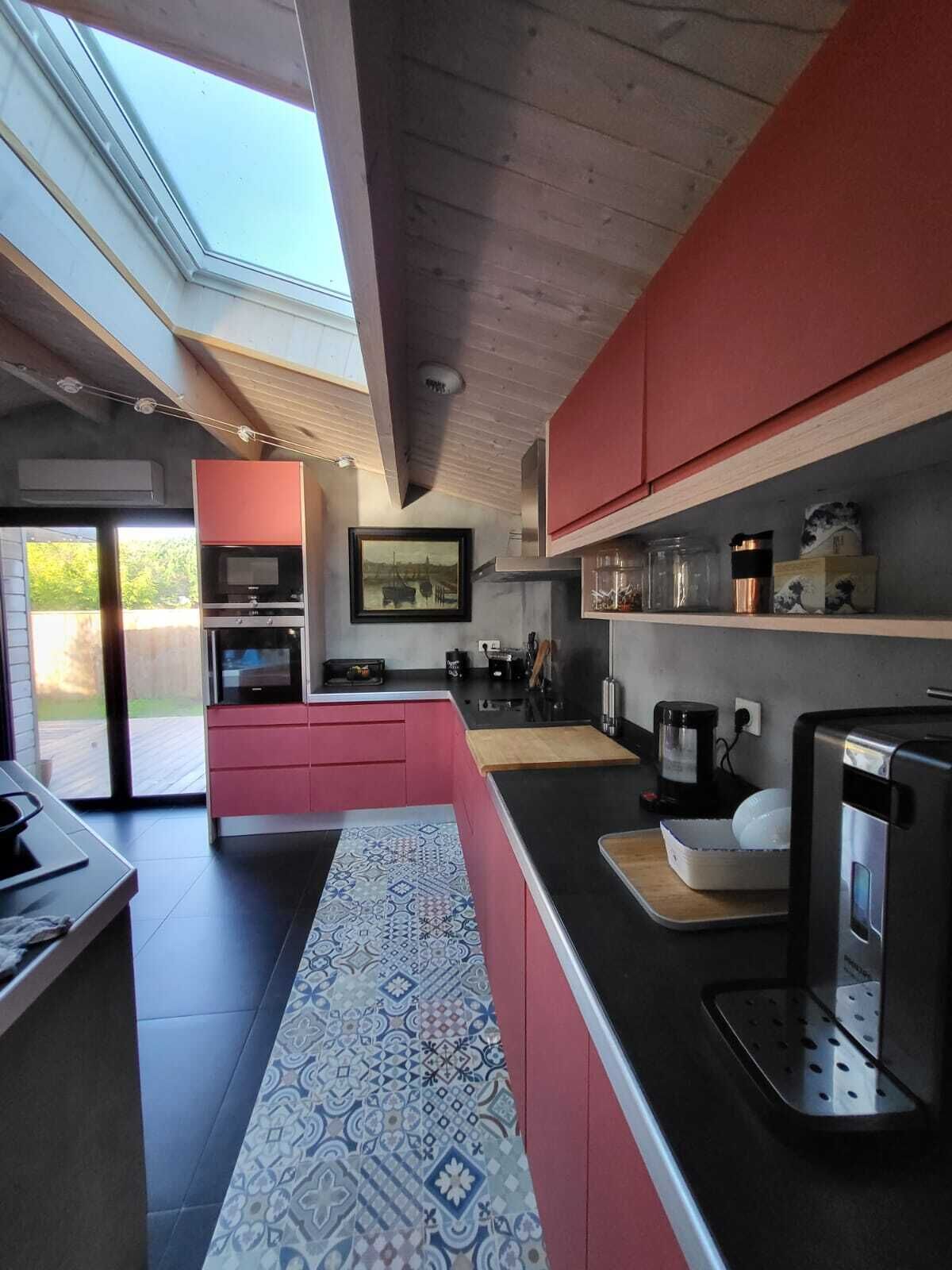 Une cuisine moderne dotée d’une verrière, de meubles de couleur rouge et d’un crédence décorée.