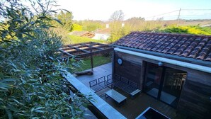 Una casa moderna con techo de tejas, terraza de madera y un pequeño espacio de estar al aire libre.