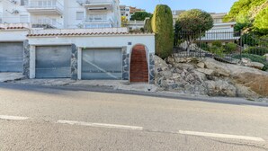 A residential building with a stone facade, a red door, and a stone wall. - EDEN MAR 1A Roses (Rosas / Roses)