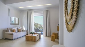Een moderne woonkamer met een bank, salontafel en uitzicht op een heuvel.
